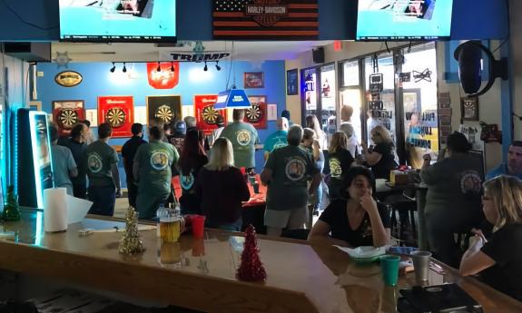 The interior of the Pelican Pub with a crowd facing the back wall