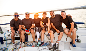 The crew of a sailboat, sitting along the deck