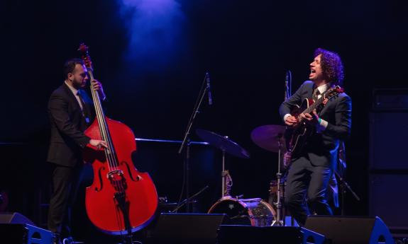 Alberto Cebellero on guitar on stage with his trio, which includes a bass player and a drummer