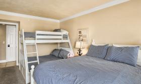 A bedroom with one queen and a set of bunkbeds in a vacation condo