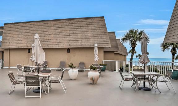 A rooftop deck with umbrella tables and a view of the ocean