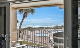 The view of pool deck and beach from one unit in a beachside condo