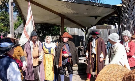 Members of the encampment gather near a Spanish Flag