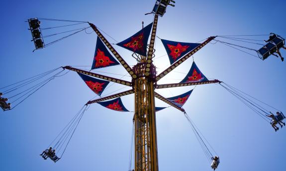 A fairground swing operating against a blue sky