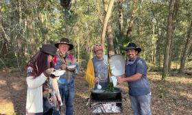A group around cooking fire at the Holistic Gathering and Plant Swap in Elton