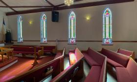 sunlight drifts onto red pews through the stained glass windows in st paul ame church in st augustine florida