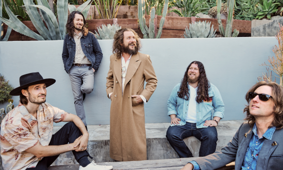 Members of the band smile and pose in their jackets.