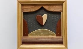 A piece of wood art by Ron Vellucci that looks like a stage with a heart behind the open curtains