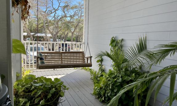 A hammock and plants are positioned on the deck. 