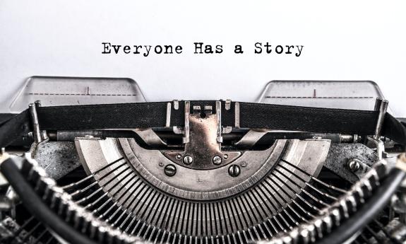 A classic old, black typewriter against a white background with the heading, "Everyone Has a Story"