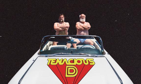 Jack Black and Kyle Gass in swimsuits sitting in the back of a white convertible
