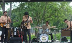 Members of the Beatles tribute band, outdoors at a concert