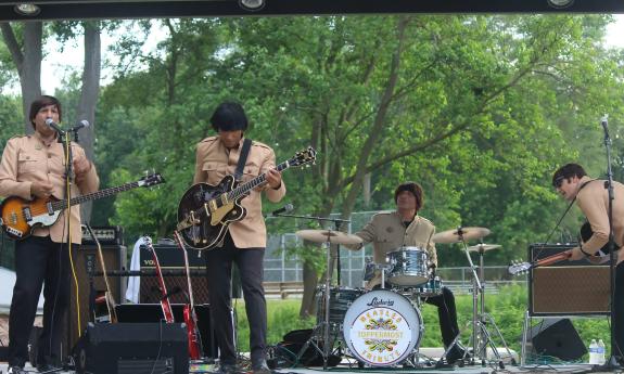 Members of the Beatles tribute band, outdoors at a concert