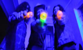 Three members of Indie Rock band Naum pose with fluorescent water guns