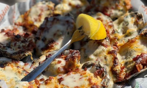 A platter of roasted oysters, baked with house-made spinach and crab dip and topped with bacon