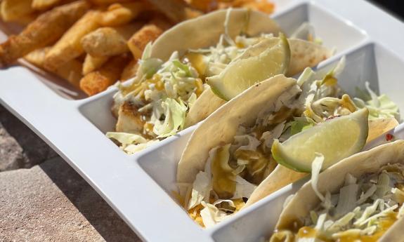 Three tacos and fries in a special white platter from Crabby's Beachside 