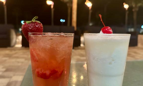 Two festive drinks with fruit, sitting on a table at Crabby's Beachside in St. Augustine Beach at night