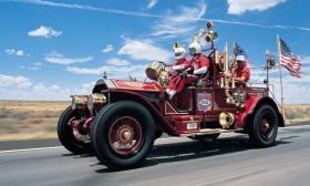 An antique fire truck competing in an earlier Great Race, driving past a desert