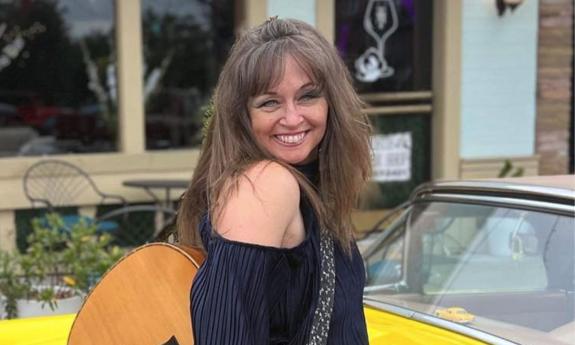 Michelle Ingrhman with her guitar in front of a yellow car
