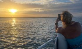 A tourist aboard the Tiki Island Adventures boat, takes a photo of the sunset in St. Augustine