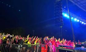 This colorful photo of a crowd near the stage at the As If! Fest, being bathed by the bright red and yellow lights 