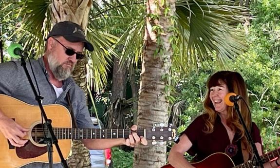 Lee Huntere holding a guitar, smiling and singing, while Joey Kerr plays guitar.