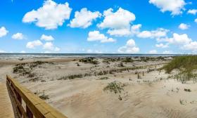A glimpse of a private boardwalk from Ocean & Racquet Resort, and a view of dunes and the Atlantic Ocean on St. Augustine Beach