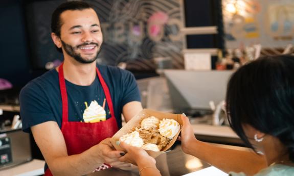 An employee serves a tray of waffles to a customer