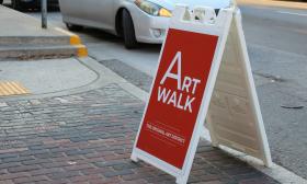 A red sandwich-board sign announcing Art Walk on First Friday in St. Augustine