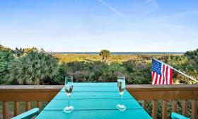 Two glasses of champagne on a balcony table, overlooking the dunes and the ocean from St. Augustine Ocean & Racquet Resort