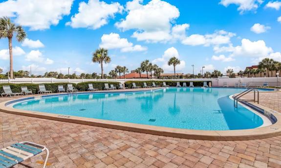 A view of one of the pools at St. Augustine Ocean & Racquet Resort, with a brick deck, and lounge chairs