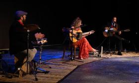 The three members of Zaza Flamenca, on stage, percussionist, and two vocalists with guitars