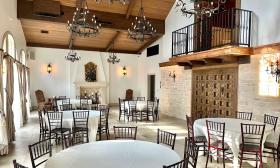 The interior of 9 Aviles Event Space shows round tables, old-fashioned wood chairs and the balcony