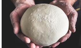 A man holds dough in his hands. 