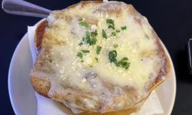 French onion soup with scallions are placed in a bowl.