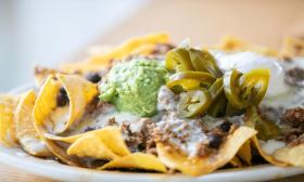 Nachos with beans, beef, guacamole, jalapenos, and queso dip from Playa Chac-Mool