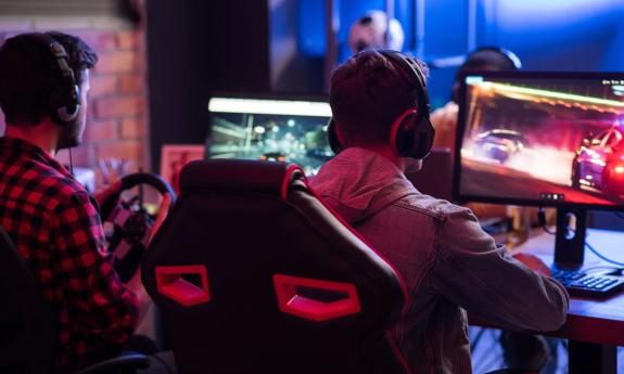 Two children play on a gaming system with large monitors. 