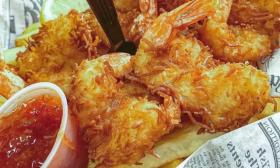 Shrimp and sauce is placed in a basket lined with newspaper strips