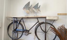 A hall table made with parts from an old bicycle, with two painted tin fish on top