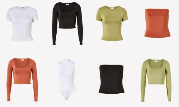 Colorful shirts and bodysuits are positioned in front of a white background. 