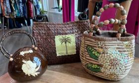 Three purses with a coastal theme are positioned on a table in the boutique. 