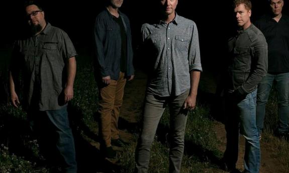  Smalltown Poets pose in front of a black background. 