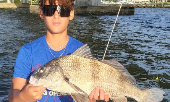 A boy, holding a fish he caught with Aloha Fishing Charter in St. Augustine.