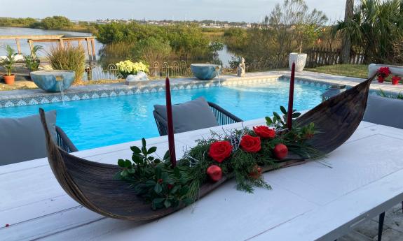 An arrangement of roses and greens fill a gondola-shaped table centerpiece