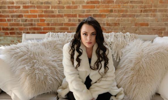 Mindy Smith sits on a plush white couch and smiles for the camera. 