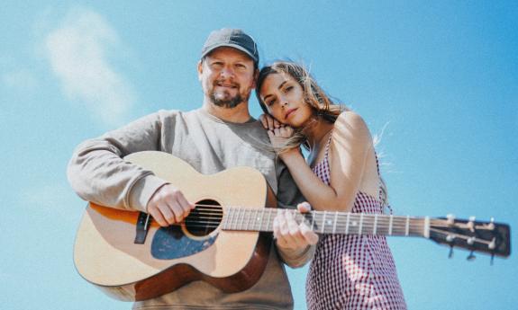Ocie Elliott smiles and poses with a guitar.