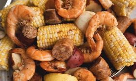 Corn and shrimp is placed in a pot.