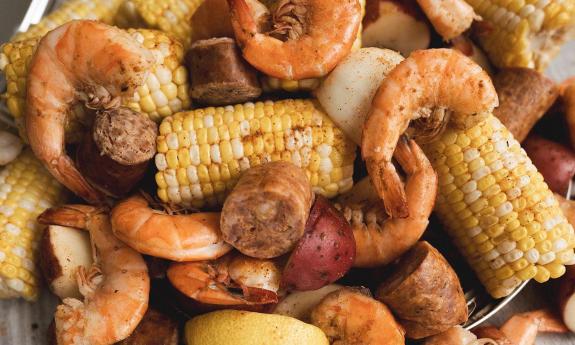 Corn and shrimp is placed in a pot.