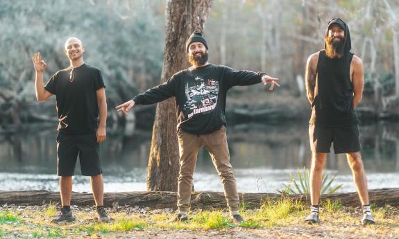 Members of Sensation pose in front of a tree and a river. 