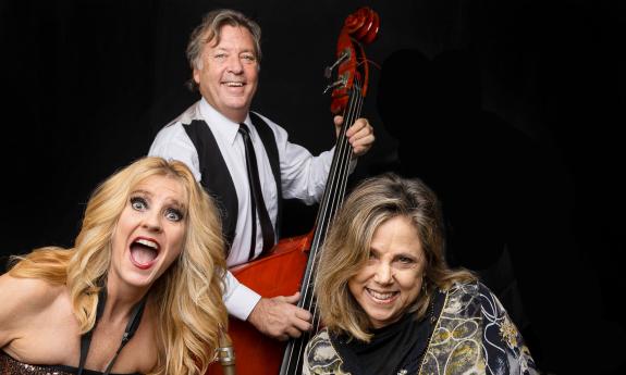 The three members of the Teal Cabana Band smiling against a black background.